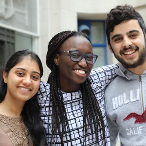 Three students stand with their arms over each other's shoulders